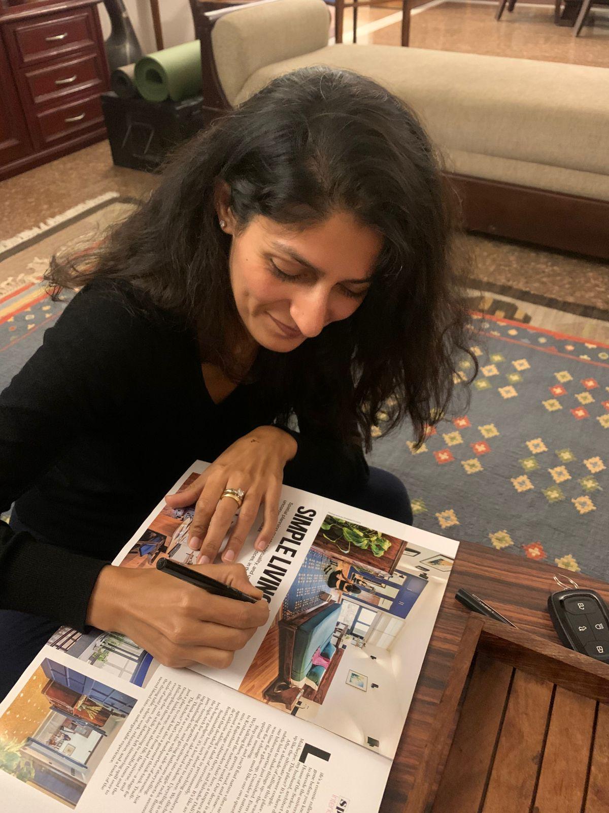 Shreenu Mukherjee signing a magazine copy containing her published work, as a memento for the editor